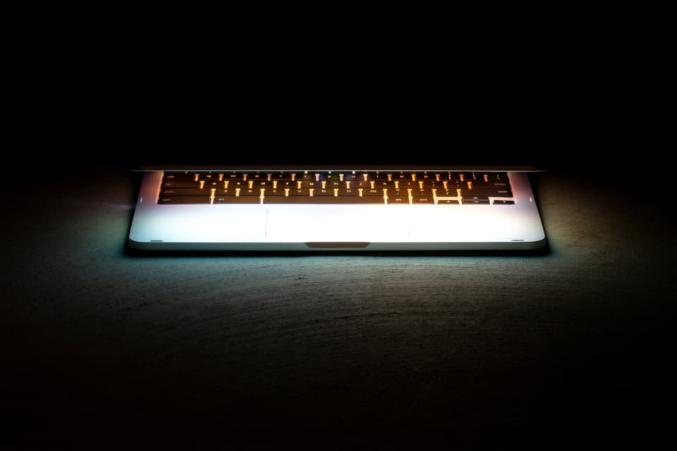 A laptop keyboard glowing in a dark room